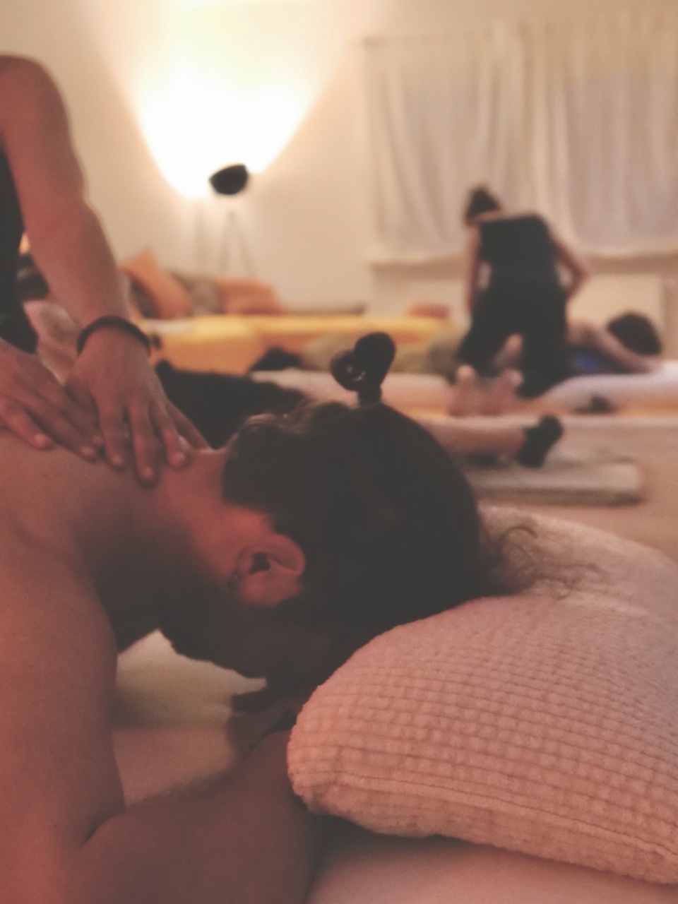 Paar-Massage: Hände auf den Schultern einer liegenden Person