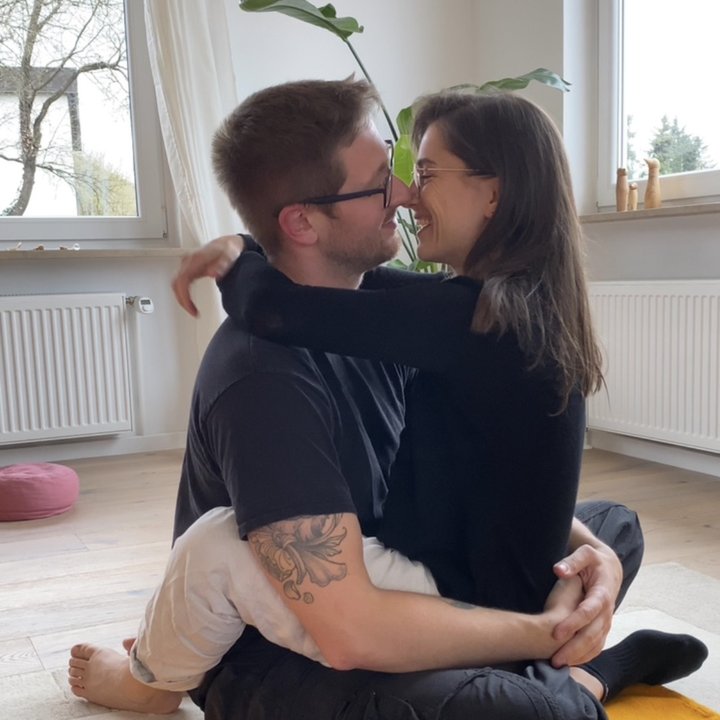 Annika und Marco sitzen umarmt auf dem Boden ihres Praxisraums