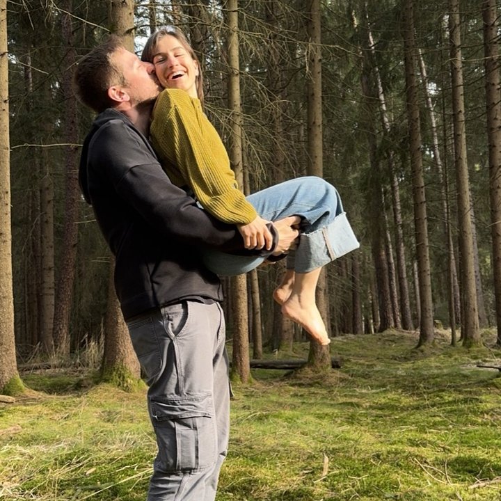 Marco hebt Annika lachend hoch, im Wald